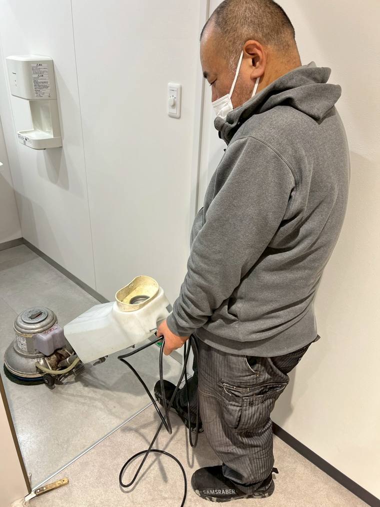 トイレの床をポリッシャーで洗浄するスタッフ