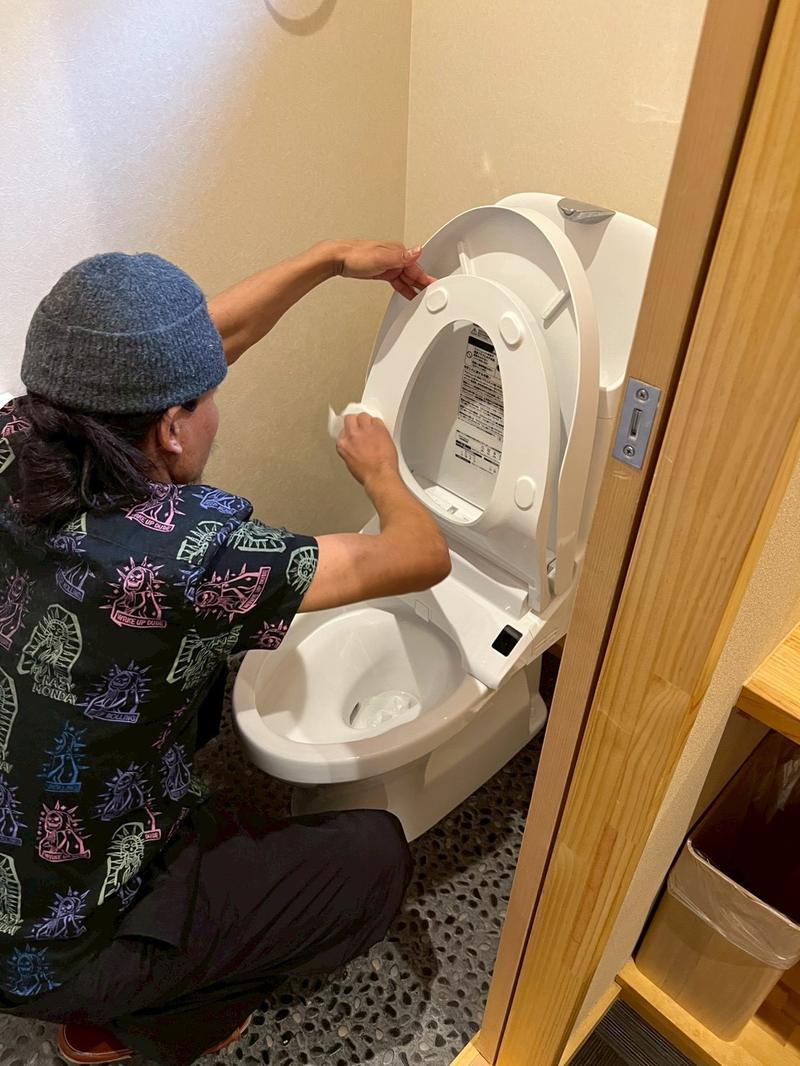 便座とフタを拭き上げるスタッフ