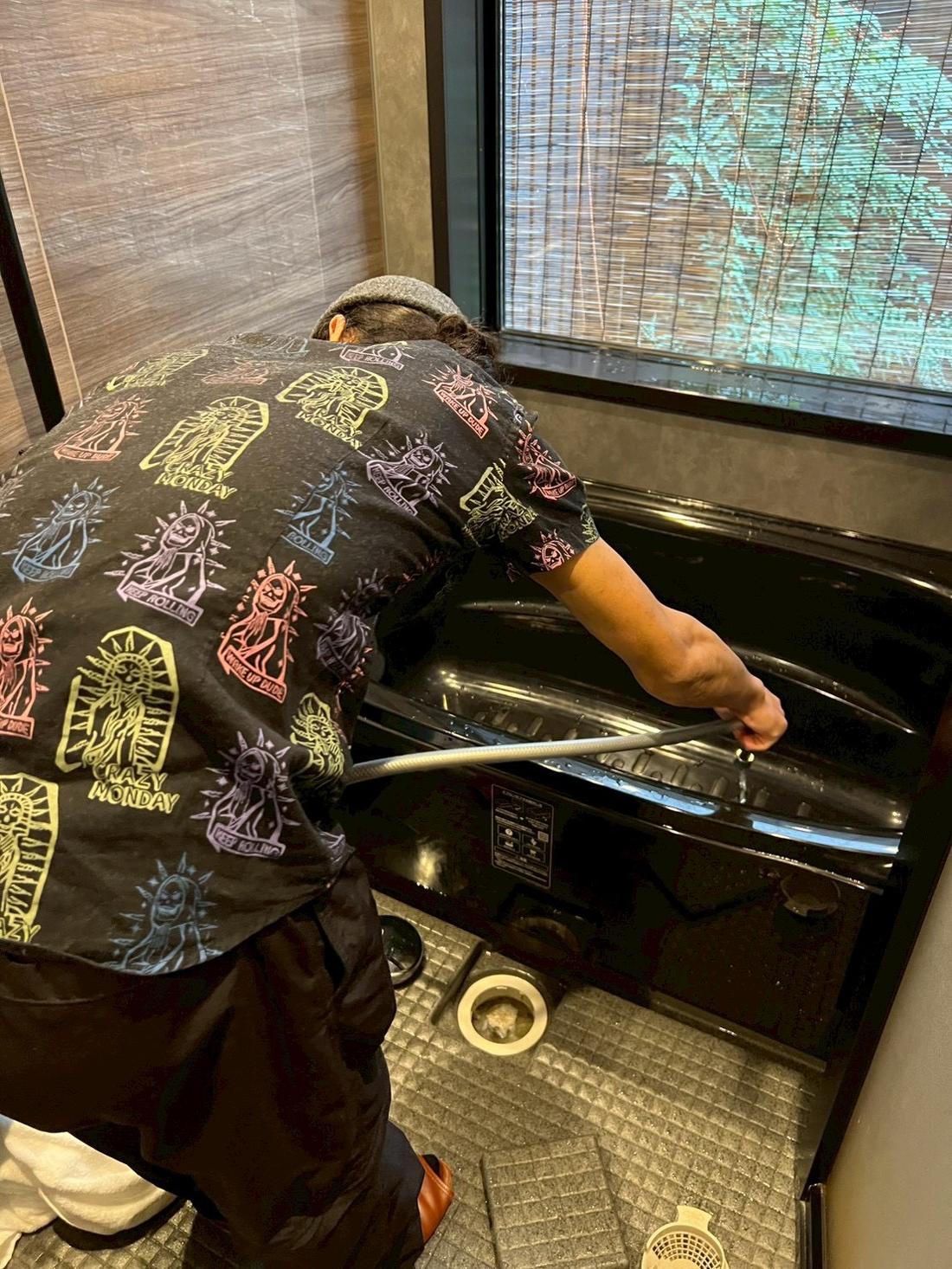 浴室の浴槽を磨くスタッフ