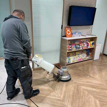 ロビーの床をポリッシャーで洗浄するスタッフ