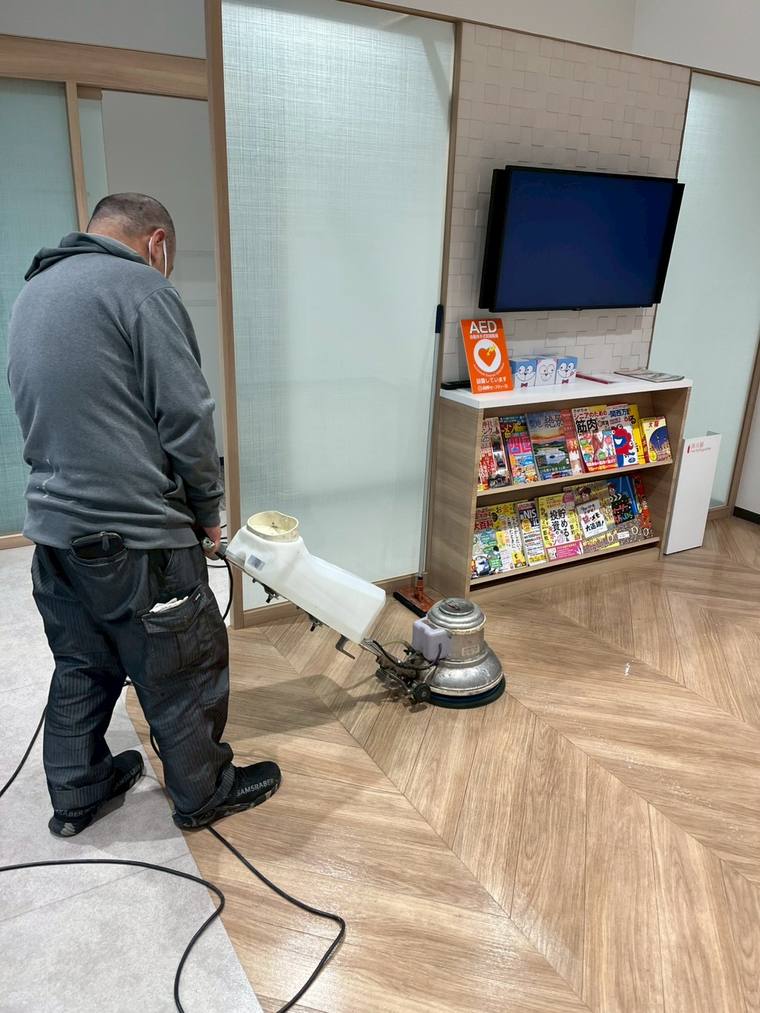 ロビーの床をポリッシャーで洗浄するスタッフ